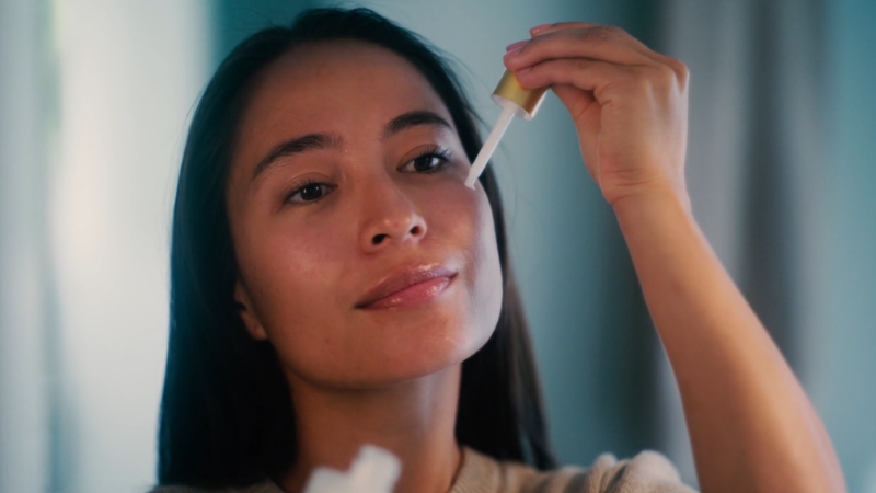 Person applying a skincare serum with a dropper as part of a routine that may include niacinamide and tretinoin