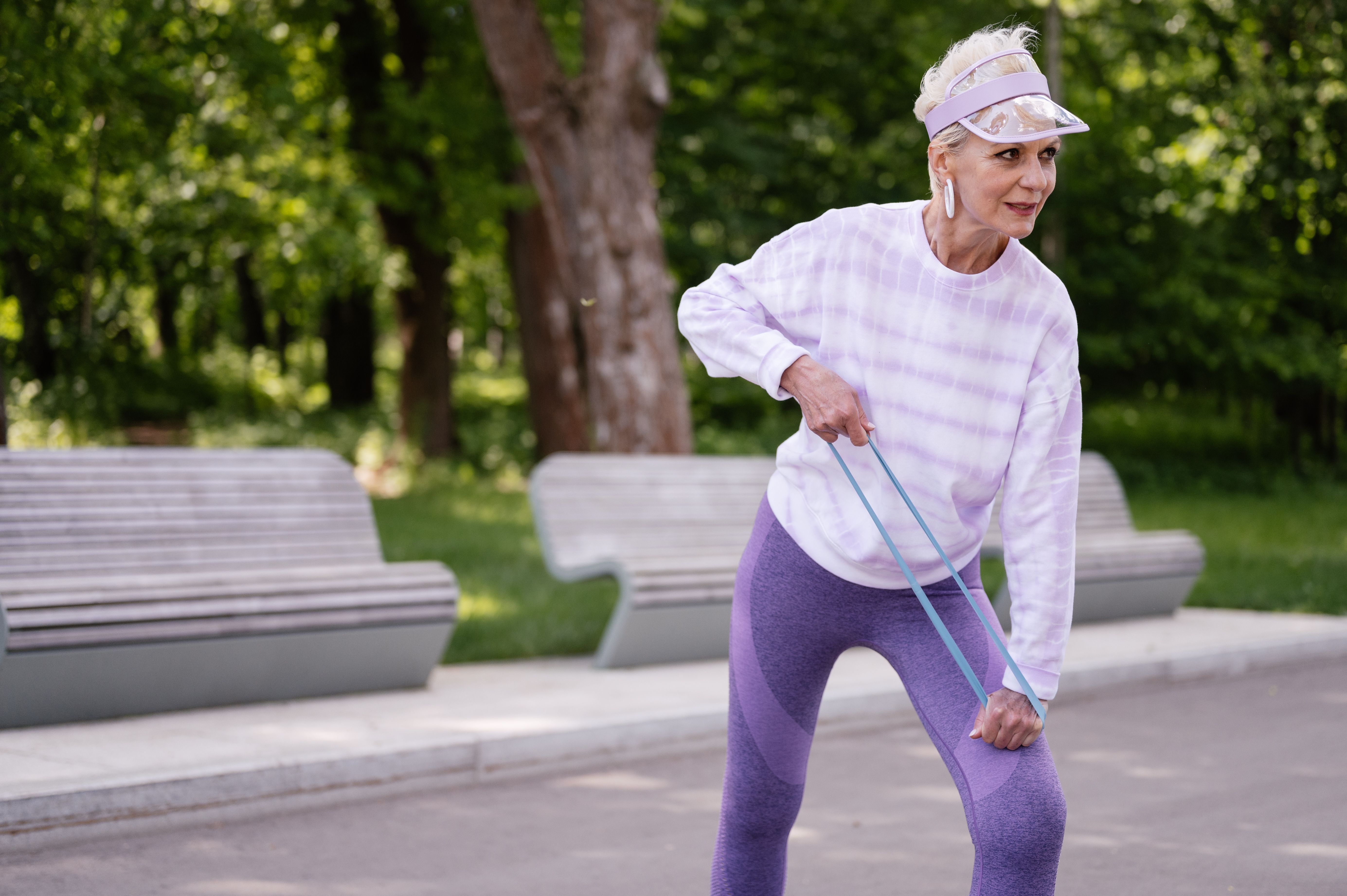 Older woman exercising with a resistance band outdoors, illustrating movement and healthy aging.