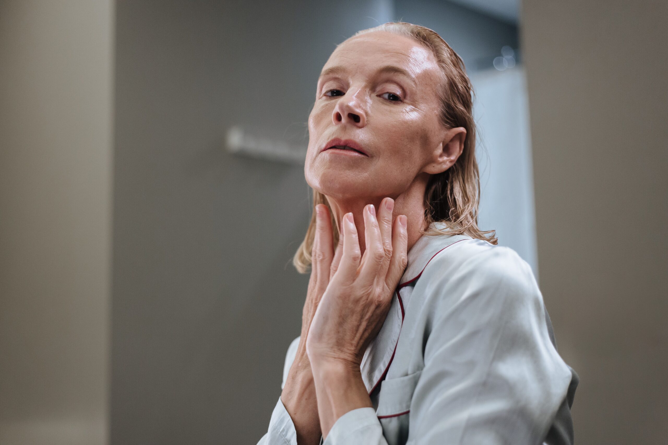 Older woman applying skincare product to her face as part of a daily skin health routine.